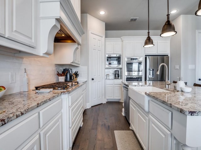 kitchen featuring visible vents, decorative backsplash, white cabinetry, a sink, and appliances with stainless steel finishes
