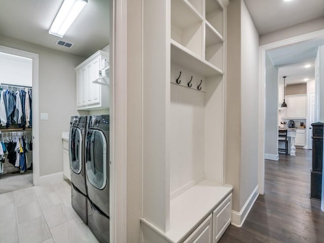 laundry room featuring visible vents, wood finished floors, baseboards, washing machine and clothes dryer, and cabinet space