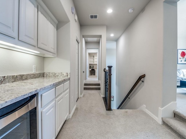 hall with light colored carpet, baseboards, an upstairs landing, wine cooler, and visible vents