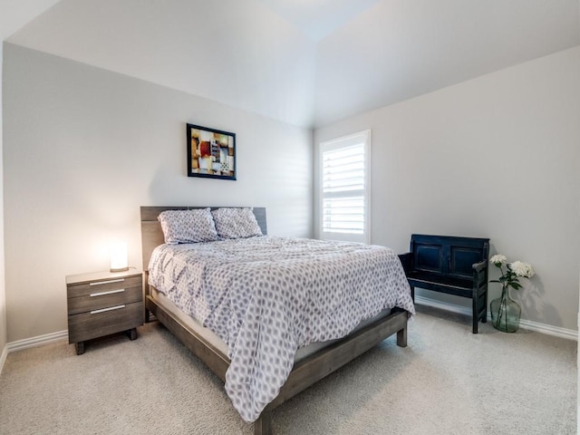 bedroom featuring baseboards, vaulted ceiling, and light colored carpet