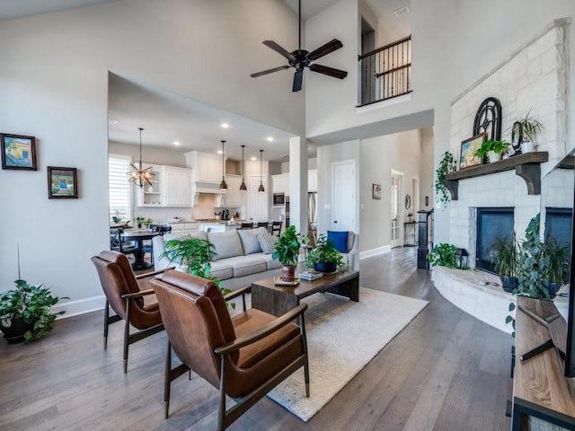 living area featuring baseboards, ceiling fan, dark wood finished floors, and a towering ceiling
