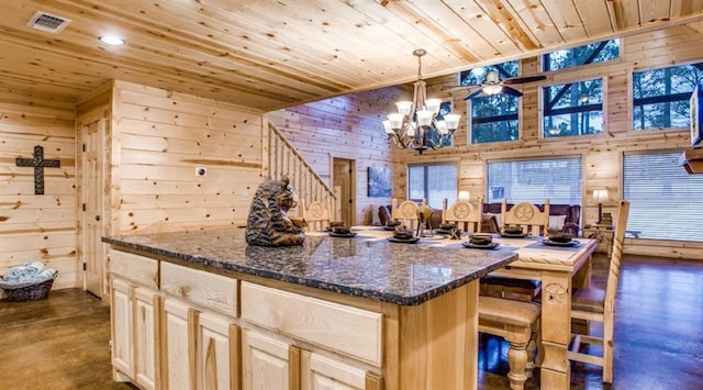 kitchen featuring wooden walls, dark stone countertops, decorative light fixtures, and a center island