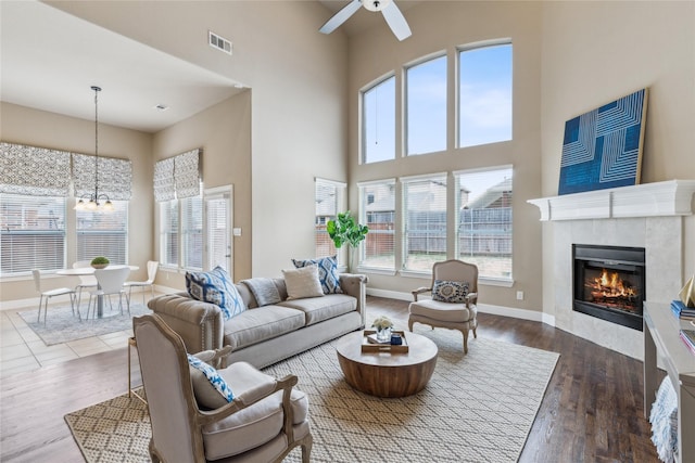 living room featuring dark wood-type flooring, baseboards, visible vents, and a tiled fireplace