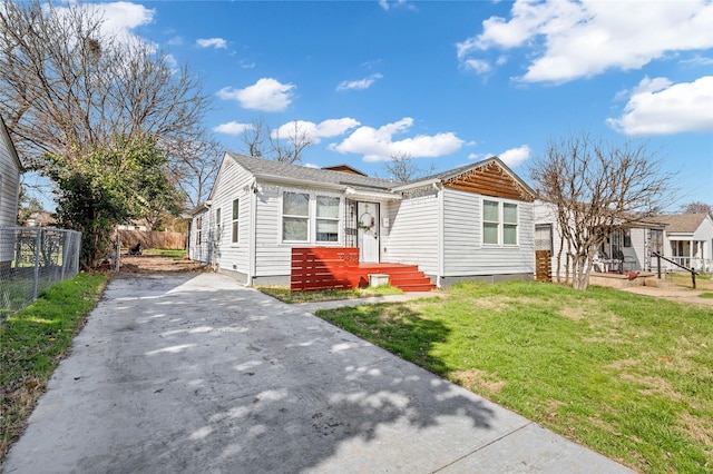 bungalow-style home with driveway, fence, and a front yard