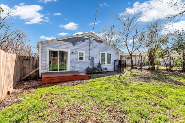 rear view of house with a fenced backyard, a wooden deck, and a yard