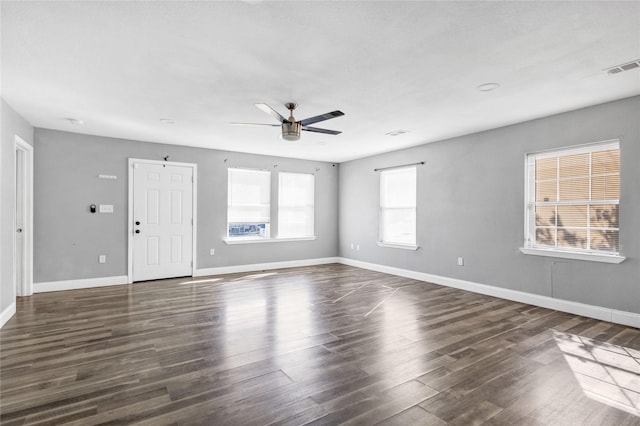 unfurnished room featuring baseboards, visible vents, dark wood finished floors, and a ceiling fan