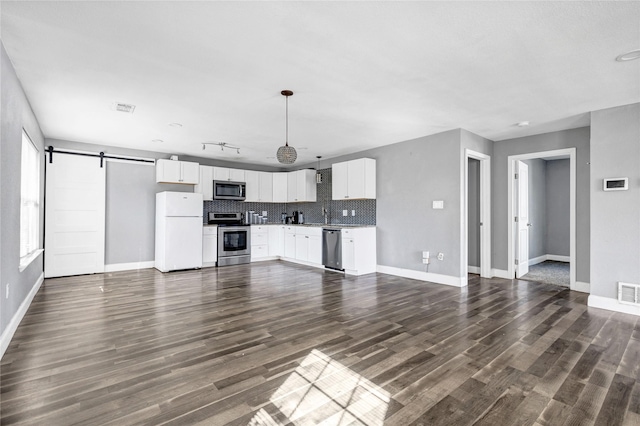 unfurnished living room with a barn door, visible vents, and dark wood-style flooring