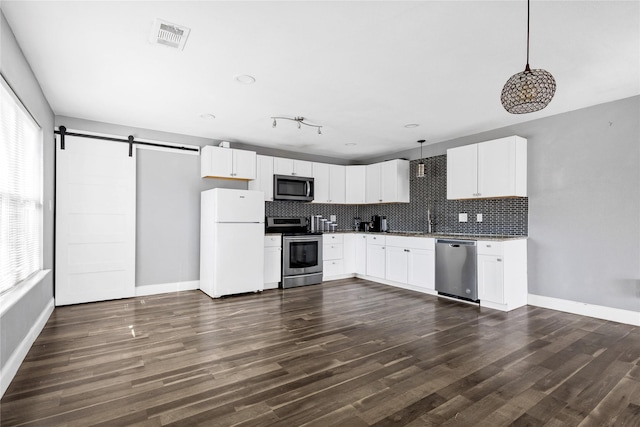 kitchen with hanging light fixtures, white cabinetry, appliances with stainless steel finishes, and a barn door