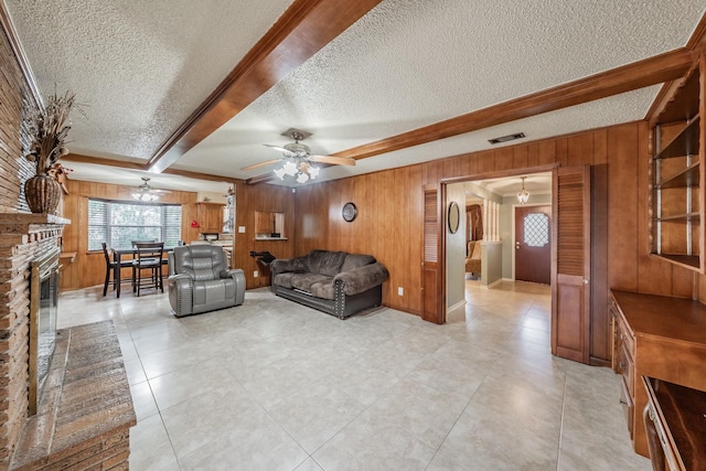 living room with wood walls, plenty of natural light, visible vents, and a brick fireplace