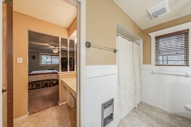 full bath with tile walls, heating unit, ensuite bathroom, a ceiling fan, and tile patterned floors