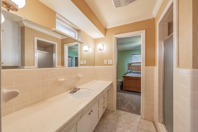 ensuite bathroom with tile patterned flooring, connected bathroom, tile walls, ornamental molding, and wainscoting