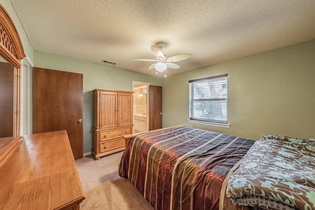 bedroom with a textured ceiling, ceiling fan, light colored carpet, visible vents, and ensuite bath