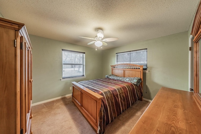 bedroom featuring light colored carpet, ceiling fan, a textured ceiling, and baseboards