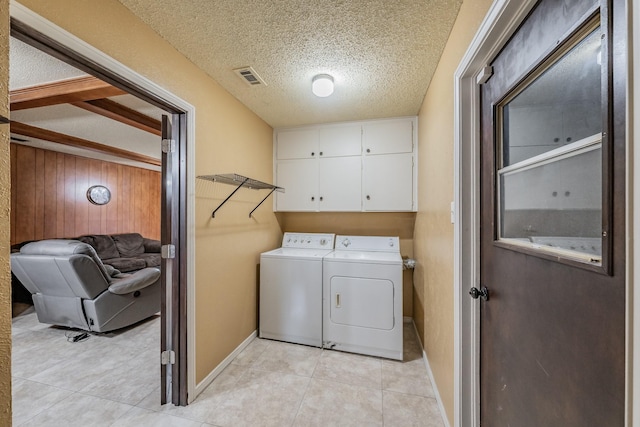 clothes washing area with cabinet space, light tile patterned floors, visible vents, a textured ceiling, and washing machine and dryer