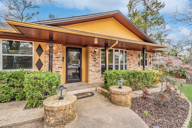 doorway to property featuring brick siding and stucco siding