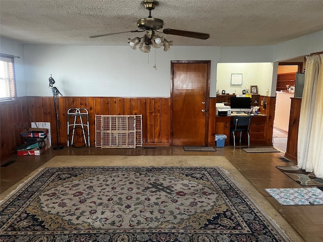 office area featuring wainscoting, wooden walls, and a textured ceiling