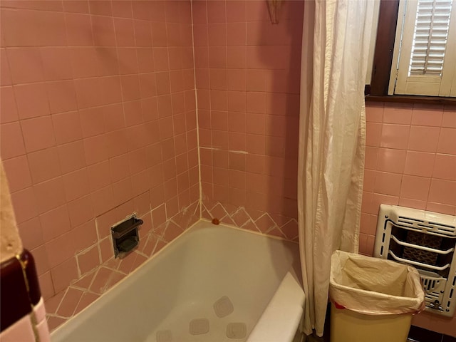 bathroom with heating unit, shower / bath combo with shower curtain, and tile walls