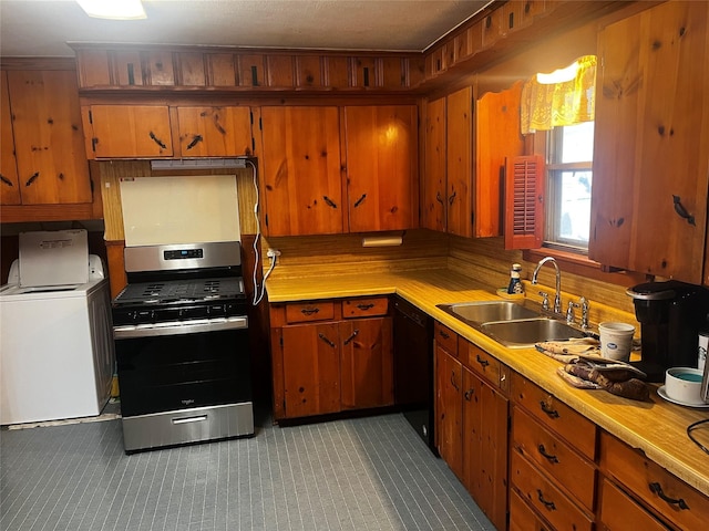 kitchen featuring a sink, black dishwasher, light countertops, stainless steel gas range, and washer / dryer