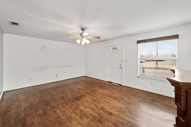 interior space with dark wood-type flooring, visible vents, baseboards, and a ceiling fan