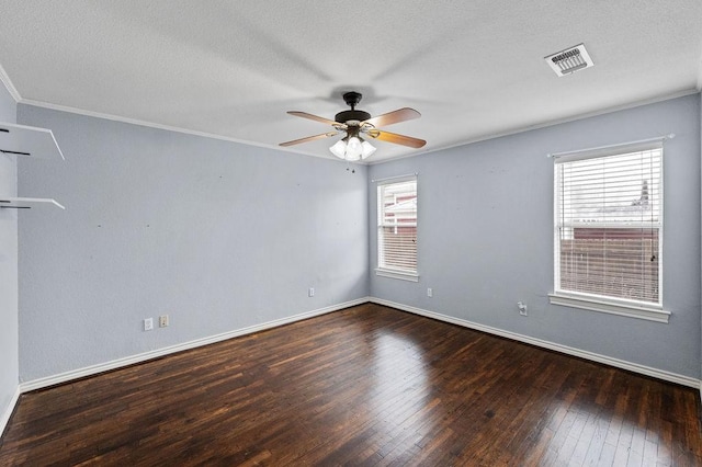 spare room featuring dark wood-style flooring, crown molding, visible vents, a ceiling fan, and baseboards