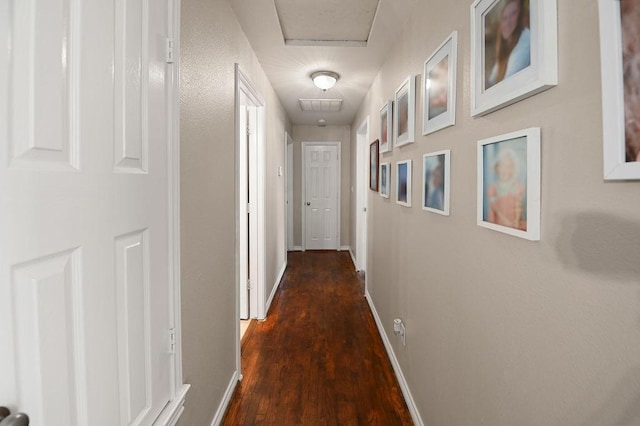 hallway with dark wood-type flooring, visible vents, and baseboards