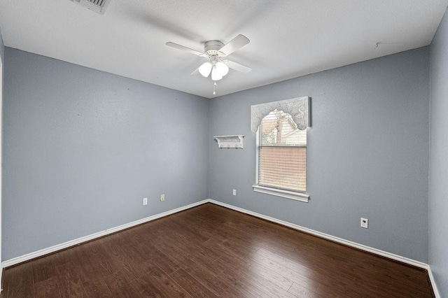 spare room with ceiling fan, visible vents, baseboards, and wood finished floors