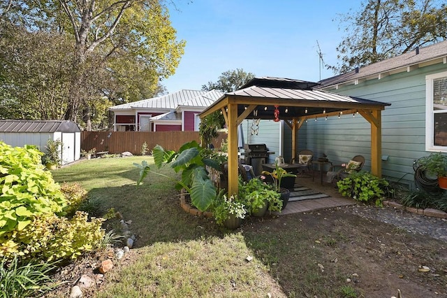 view of yard with a fenced backyard, a storage unit, an outbuilding, and a gazebo