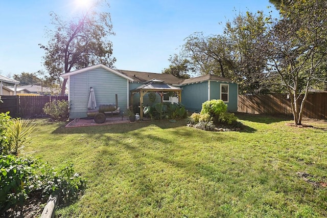 rear view of house featuring a fenced backyard, a lawn, and a gazebo