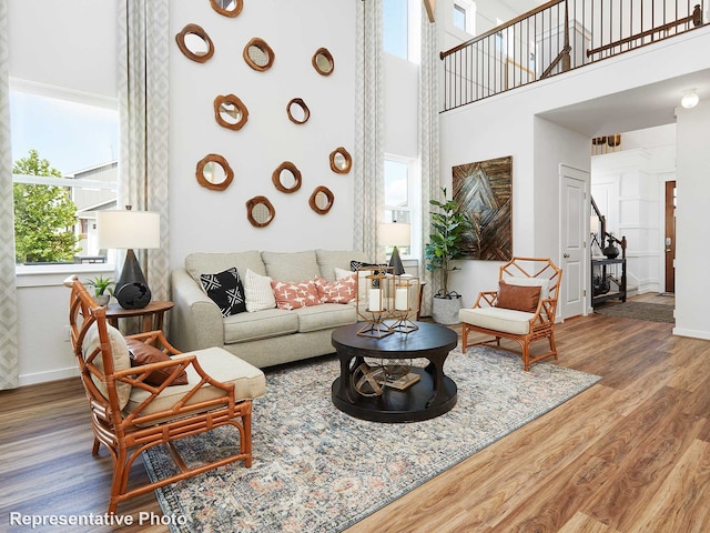 living room with a towering ceiling, baseboards, and wood finished floors