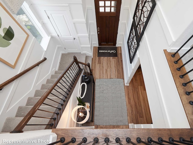 entrance foyer with a decorative wall, stairway, and wood finished floors