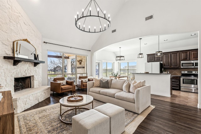 living area featuring dark wood-style floors, plenty of natural light, visible vents, and a stone fireplace