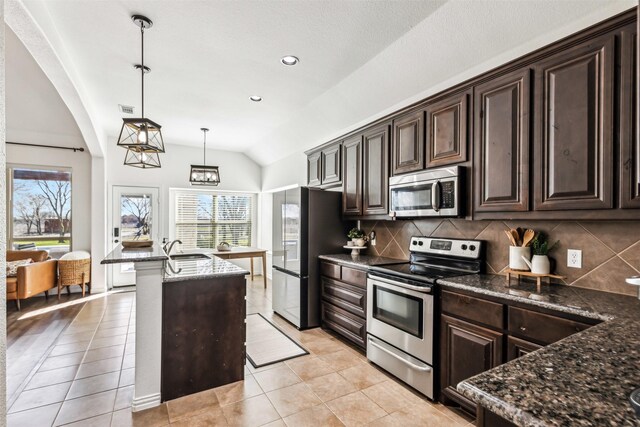 kitchen featuring vaulted ceiling, dark brown cabinets, appliances with stainless steel finishes, and pendant lighting