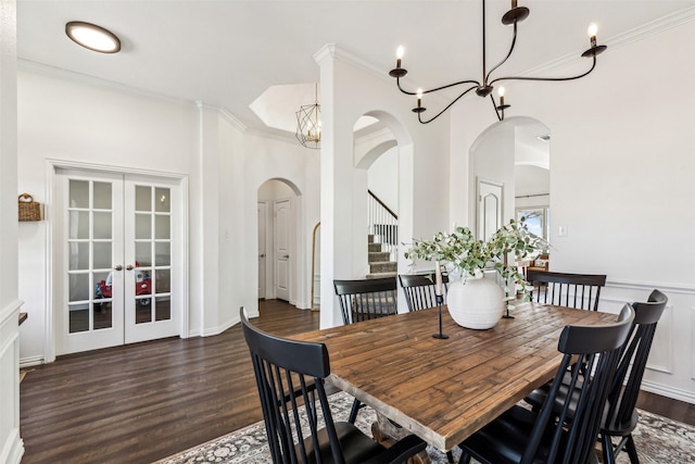 dining room with arched walkways, stairway, ornamental molding, dark wood-type flooring, and french doors