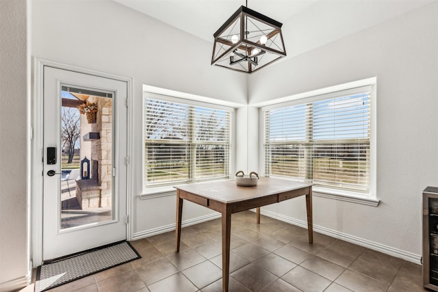 dining space featuring a chandelier, dark tile patterned flooring, and baseboards