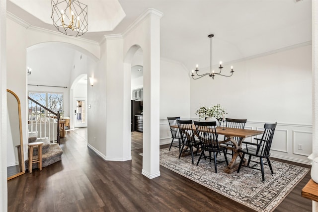 dining room with ornamental molding, dark wood-style flooring, a notable chandelier, and a decorative wall