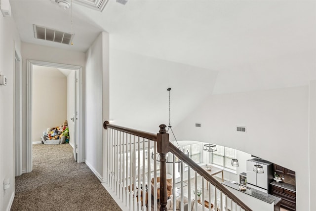 hall with baseboards, carpet floors, visible vents, and attic access