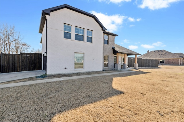 rear view of property featuring fence and brick siding