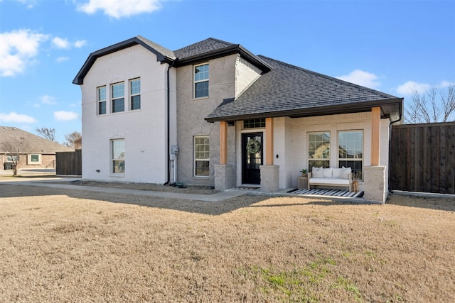 back of property featuring a shingled roof, a lawn, fence, and brick siding