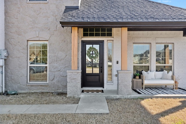 property entrance featuring brick siding, stone siding, and roof with shingles