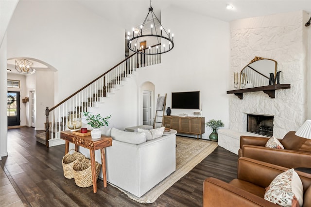 living area featuring an inviting chandelier, a fireplace, arched walkways, and dark wood-style flooring