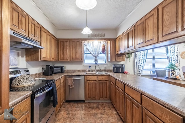 kitchen with under cabinet range hood, stainless steel appliances, a sink, ornamental molding, and brown cabinets