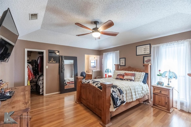 bedroom with light wood finished floors, a spacious closet, and multiple windows