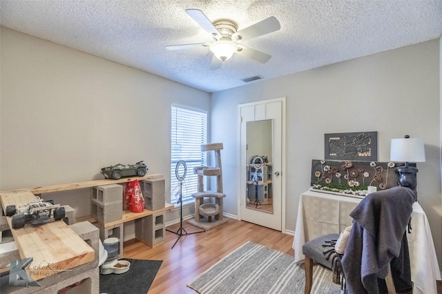 office featuring visible vents, ceiling fan, a textured ceiling, wood finished floors, and baseboards