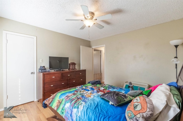 bedroom with light wood finished floors, a ceiling fan, and a textured ceiling