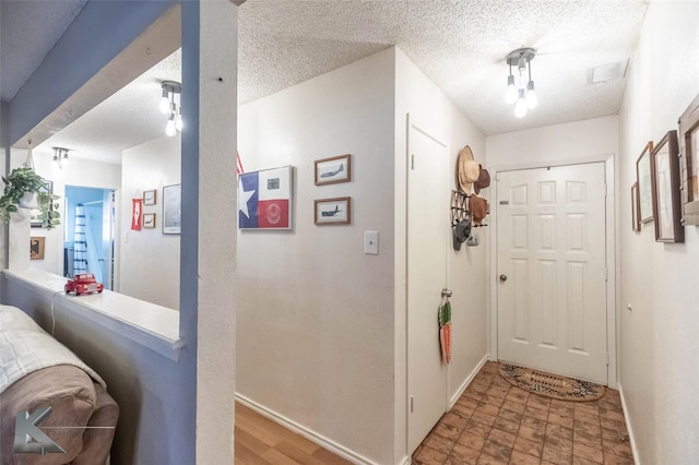 entrance foyer featuring baseboards, visible vents, and a textured ceiling