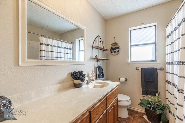 bathroom with a healthy amount of sunlight, a textured ceiling, toilet, and vanity