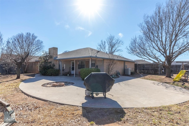 rear view of property with an outdoor fire pit, a fenced backyard, a chimney, cooling unit, and a patio area