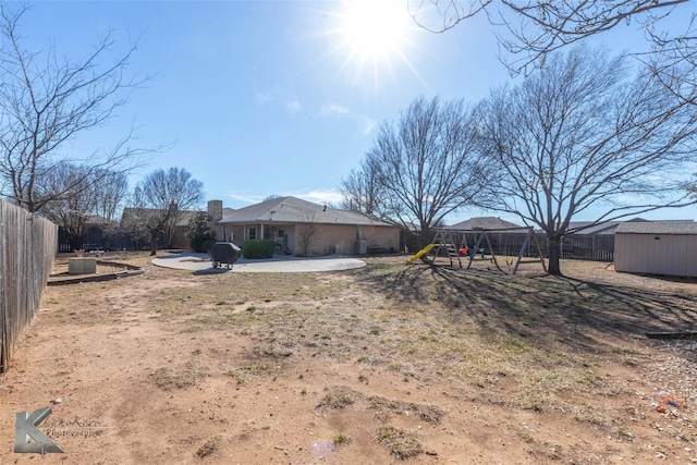 back of property featuring a patio area, a fenced backyard, a playground, and an outdoor structure