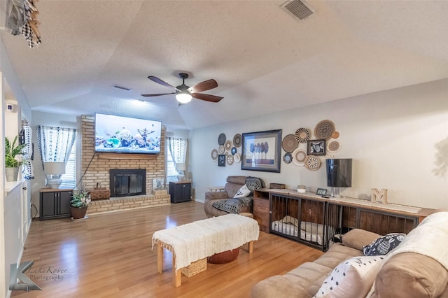 living area featuring lofted ceiling, visible vents, and wood finished floors