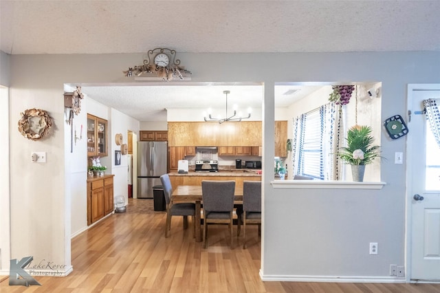 kitchen with brown cabinets, light wood finished floors, stainless steel appliances, light countertops, and a textured ceiling